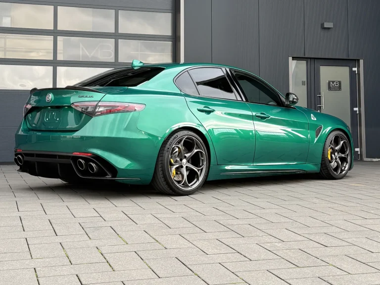 Alfa Romeo Giulia in Grün, Schrägansicht von hinten vor der Halle von MB Autopflege