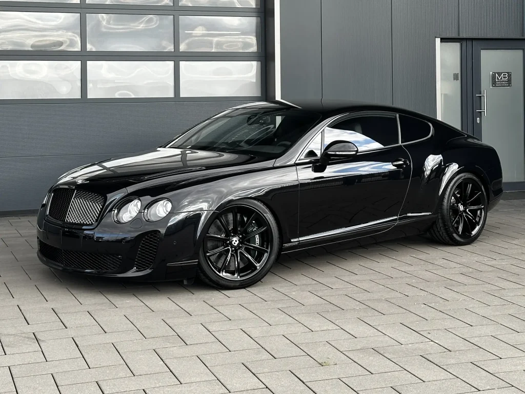Bentley Supersport in Schwarz, Schrägansicht von vorn vor der Halle von MB Autopflege