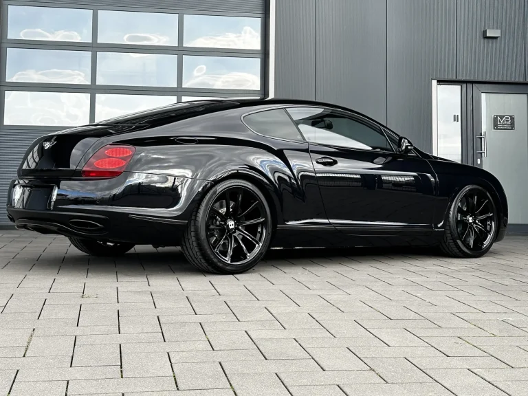 Bentley Supersport in Schwarz, Schrägansicht von hinten vor der Halle von MB Autopflege