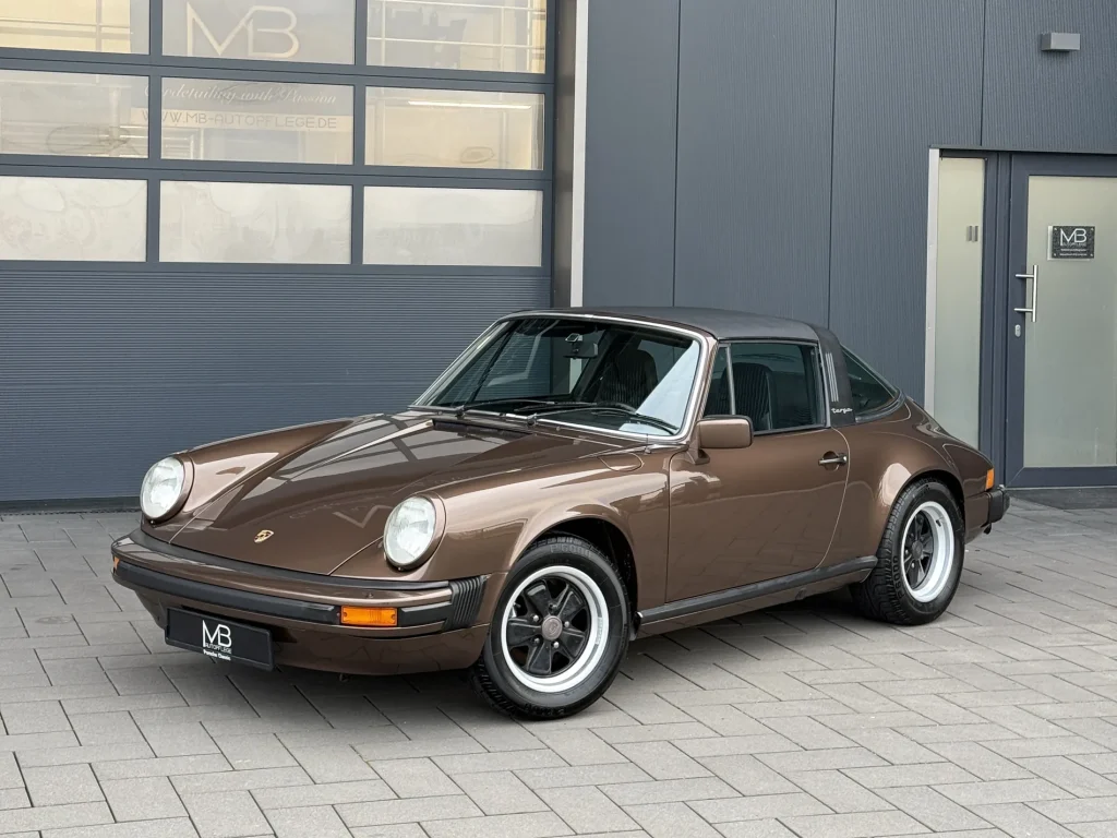 Porsche 911 3.0 in Braunmetallic, Schrägansicht von vorn vor der Halle von MB Autopflege